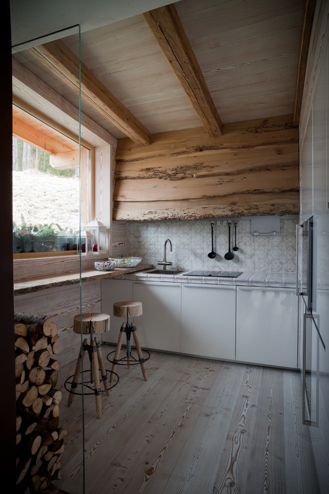 Idéer för att renovera ett litet, avskilt rustikt linjärt kök, med en enkel diskho, släta luckor, vita skåp, flerfärgad stänkskydd, integrerade vitvaror, ljust trägolv och beiget golv
