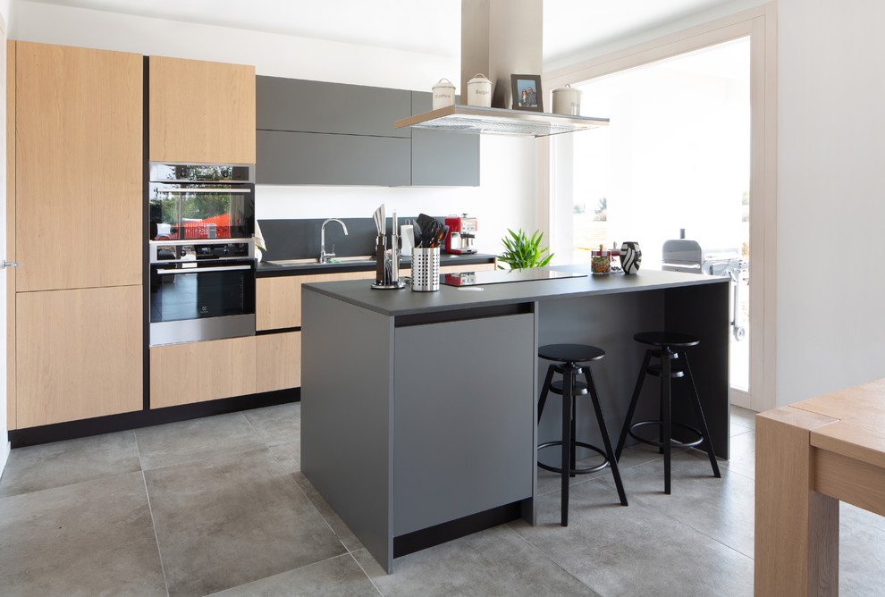 Zweizeilige Moderne Wohnküche mit flächenbündigen Schrankfronten, grauen Schränken, Küchenrückwand in Grau, Küchengeräten aus Edelstahl, Kücheninsel, grauem Boden und grauer Arbeitsplatte in Sonstige