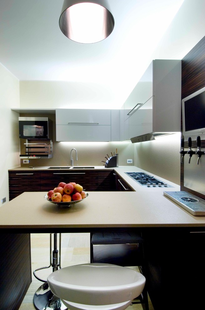 На фото: п-образная кухня-гостиная среднего размера в современном стиле с двойной мойкой, плоскими фасадами, белыми фасадами и бежевым фартуком