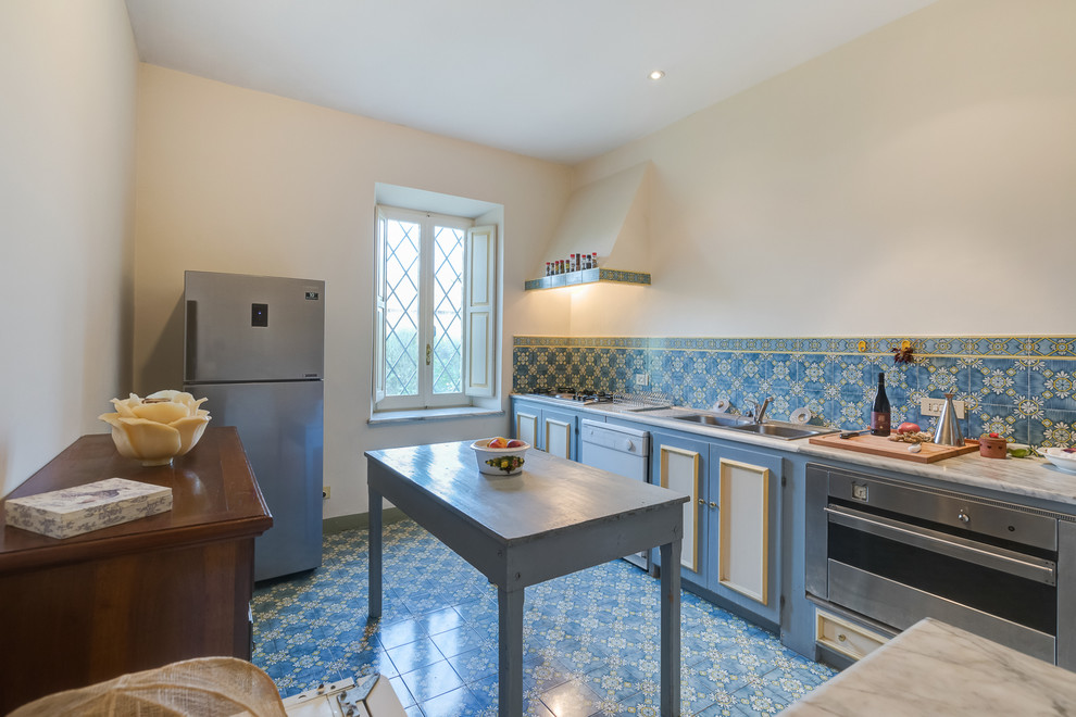 Idéer för att renovera ett mellanstort lantligt linjärt kök, med en nedsänkt diskho, blå skåp, blått stänkskydd, rostfria vitvaror, luckor med infälld panel, marmorbänkskiva, stänkskydd i keramik och klinkergolv i keramik