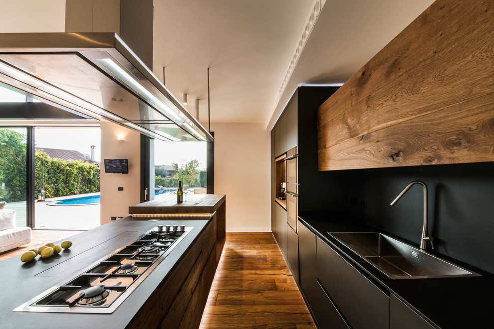 Foto på ett funkis kök med öppen planlösning, med en nedsänkt diskho, skåp i mellenmörkt trä, bänkskiva i koppar, svart stänkskydd, stänkskydd i skiffer, mellanmörkt trägolv och en köksö