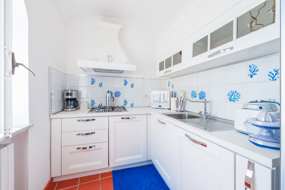 Photo of a small mediterranean l-shaped kitchen in Other with a built-in sink, recessed-panel cabinets, white cabinets, laminate countertops, white splashback, porcelain splashback, white appliances, terracotta flooring, an island, brown floors, white worktops and a vaulted ceiling.