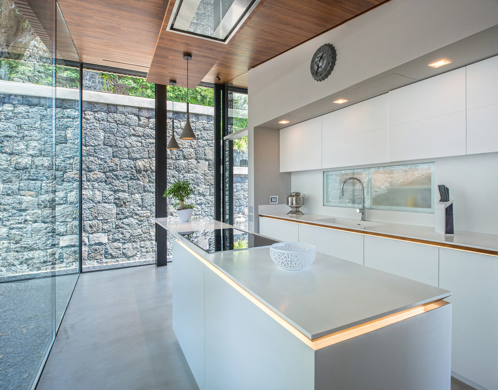 Imagen de cocina moderna con fregadero integrado, armarios con paneles lisos, puertas de armario blancas, salpicadero blanco, suelo de cemento, una isla y suelo gris