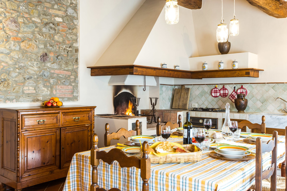 На фото: угловая кухня в средиземноморском стиле с обеденным столом, монолитной мойкой и синим фартуком без острова