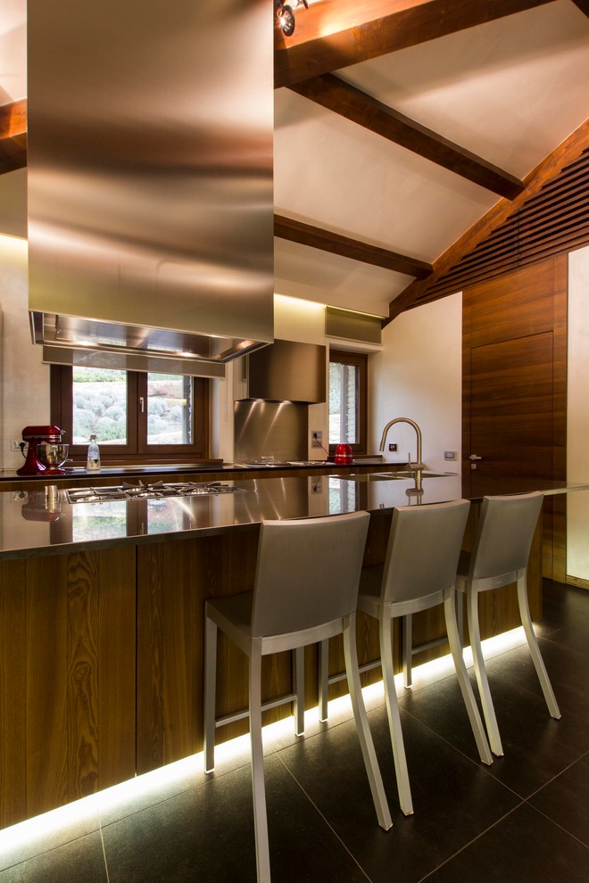 Immagine di una cucina design di medie dimensioni con ante lisce, ante in legno bruno, top in acciaio inossidabile e elettrodomestici in acciaio inossidabile