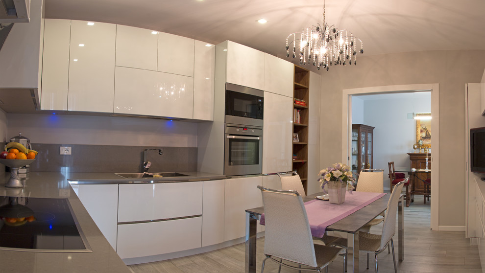 Immagine di una cucina a L minimal di medie dimensioni con ante lisce, ante bianche, top in quarzite, paraspruzzi grigio e elettrodomestici in acciaio inossidabile