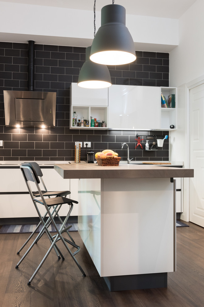 Design ideas for a large contemporary kitchen/diner in Rome with a built-in sink, flat-panel cabinets, white cabinets, dark hardwood flooring, an island, black splashback and metro tiled splashback.