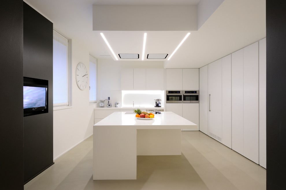 Idée de décoration pour une cuisine minimaliste en L fermée et de taille moyenne avec un évier 2 bacs, un placard à porte plane, une crédence blanche, un électroménager en acier inoxydable, îlot et un sol beige.