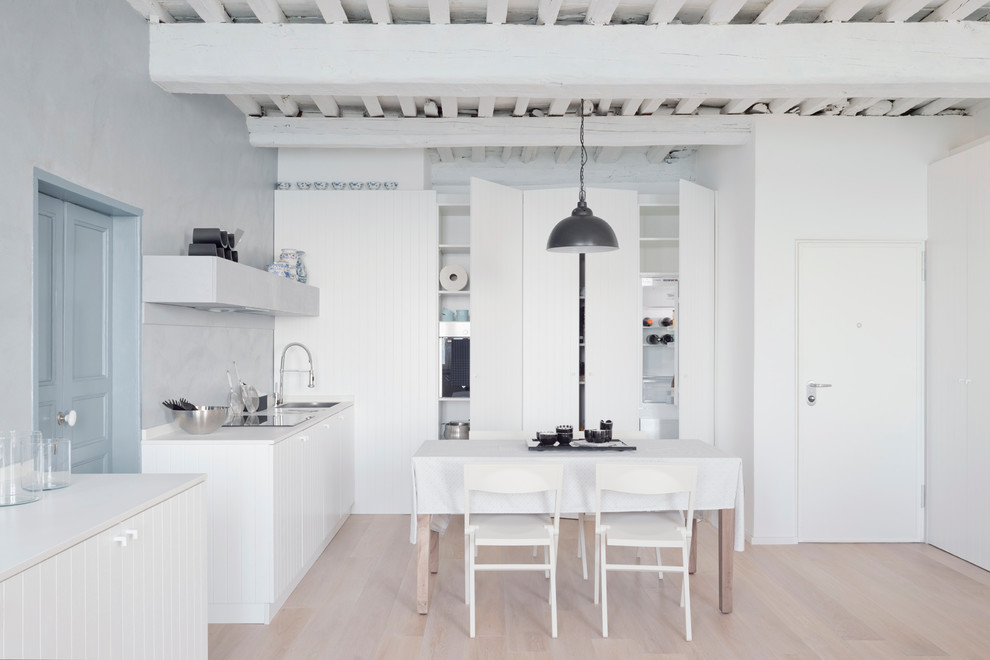 Foto på ett litet funkis vit kök, med en nedsänkt diskho, vita skåp, bänkskiva i kvarts, grått stänkskydd, vita vitvaror, ljust trägolv, beiget golv och släta luckor