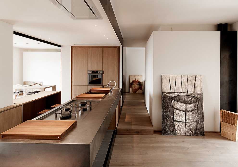 Geräumige Moderne Küche mit flächenbündigen Schrankfronten, hellbraunen Holzschränken, braunem Holzboden und Kücheninsel in Mailand