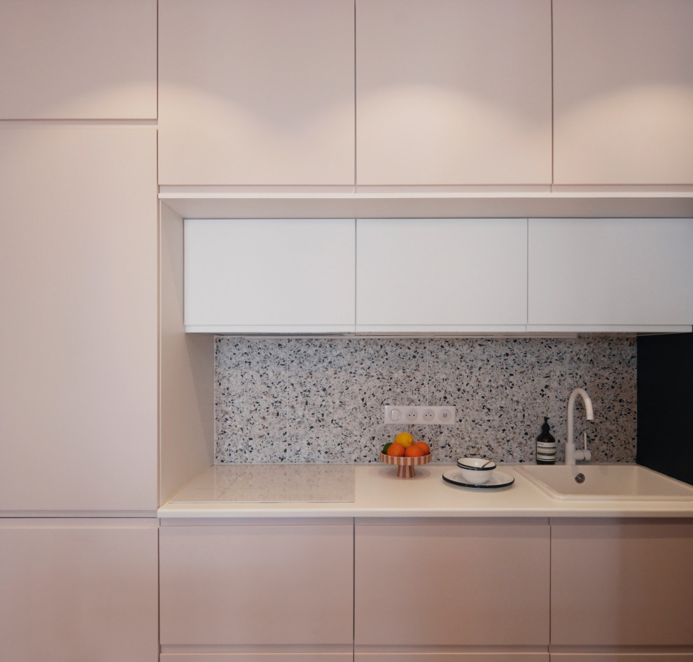 Inredning av ett modernt litet vit linjärt vitt kök med öppen planlösning, med en enkel diskho, luckor med profilerade fronter, laminatbänkskiva, flerfärgad stänkskydd, stänkskydd i keramik, vita vitvaror, vinylgolv och beiget golv