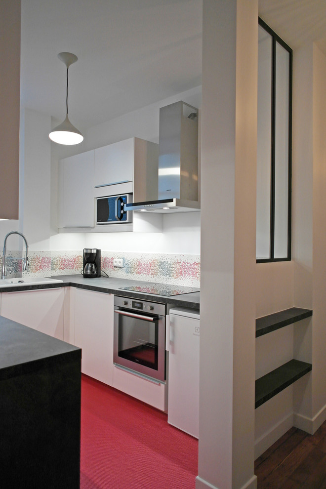 Exemple d'une cuisine encastrable tendance en U fermée et de taille moyenne avec un évier posé, des portes de placard blanches et moquette.