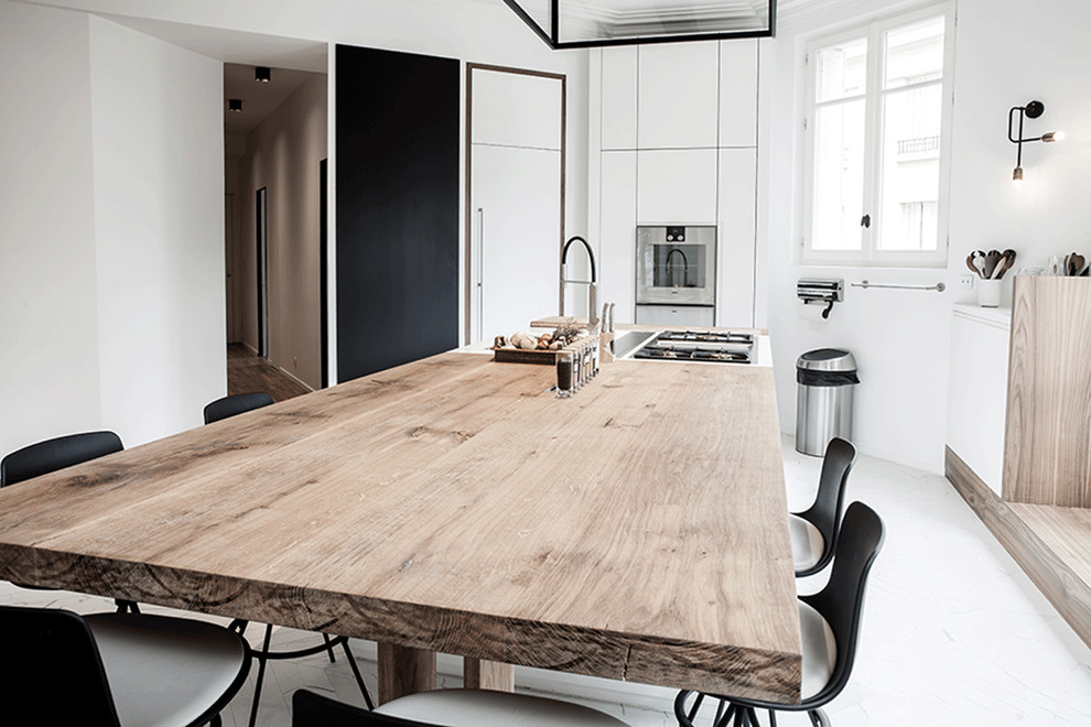 パリにある高級な巨大なコンテンポラリースタイルのおしゃれなキッチン (一体型シンク、フラットパネル扉のキャビネット、白いキャビネット、木材カウンター、シルバーの調理設備、大理石の床) の写真