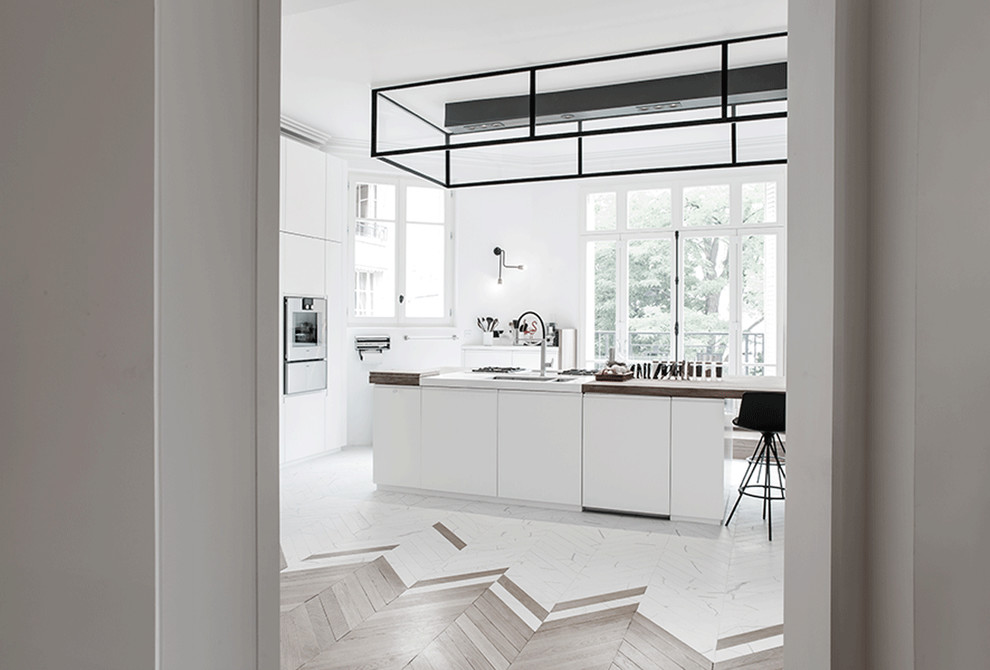 Идея дизайна: огромная кухня-гостиная в современном стиле с монолитной мойкой, плоскими фасадами, белыми фасадами, деревянной столешницей, техникой из нержавеющей стали, мраморным полом и островом