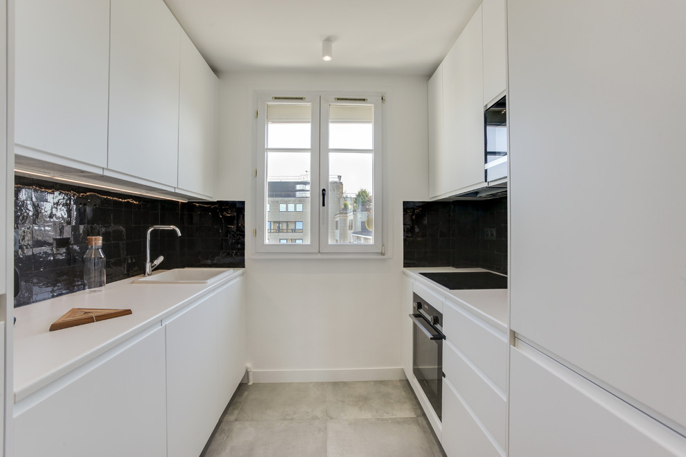 This is an example of a medium sized scandi galley open plan kitchen in Paris with a single-bowl sink, white cabinets, laminate countertops, black splashback, terracotta splashback, stainless steel appliances, ceramic flooring, grey floors and white worktops.