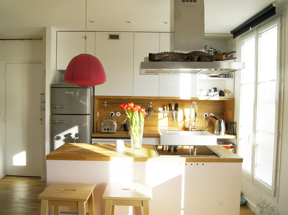 Esempio di una cucina scandinava di medie dimensioni con ante a filo, top in legno e parquet chiaro