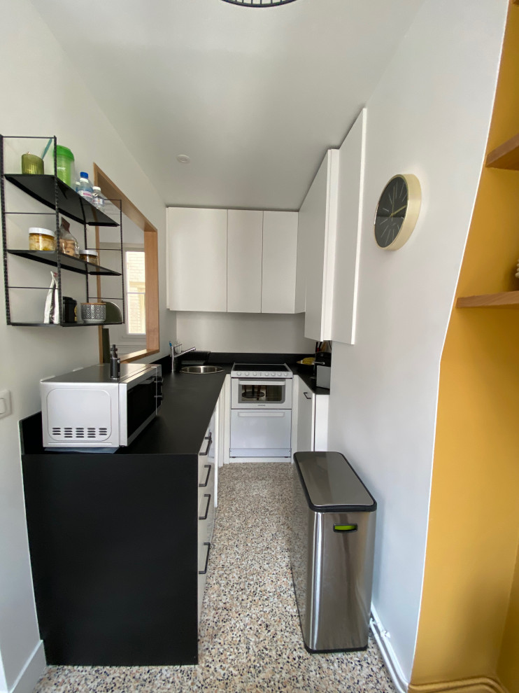 Foto di una piccola cucina minimal con ante a filo, ante bianche, top in quarzo composito, paraspruzzi nero, pavimento alla veneziana, pavimento multicolore e top nero
