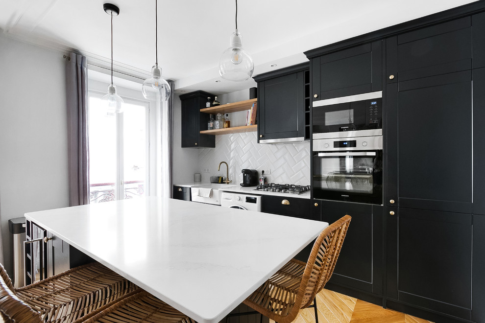 Idéer för ett modernt vit kök, med en rustik diskho, skåp i shakerstil, svarta skåp, vitt stänkskydd, stänkskydd i keramik, svarta vitvaror, mellanmörkt trägolv, en köksö och beiget golv