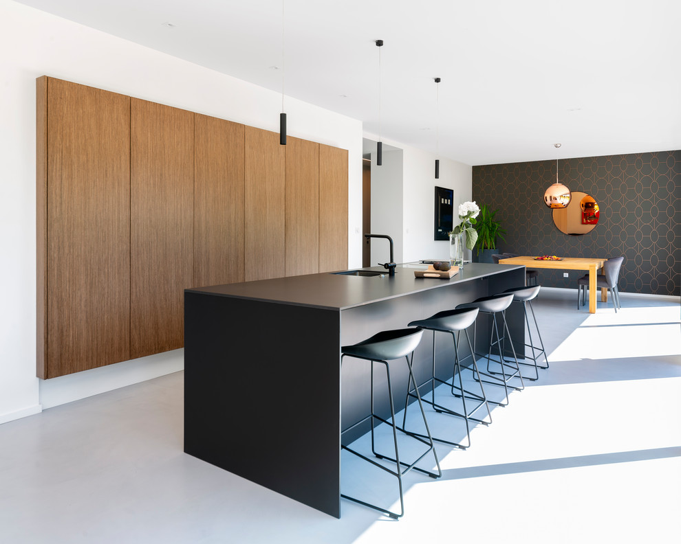 Design ideas for a large contemporary kitchen/diner in Nantes with flat-panel cabinets, concrete flooring, an island, grey floors, black worktops, medium wood cabinets and a single-bowl sink.
