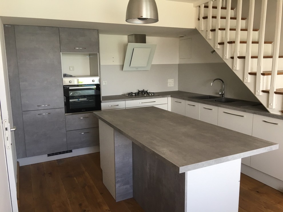 Example of a mid-sized minimalist l-shaped dark wood floor open concept kitchen design in Rennes with a double-bowl sink, laminate countertops, gray backsplash, stainless steel appliances and an island