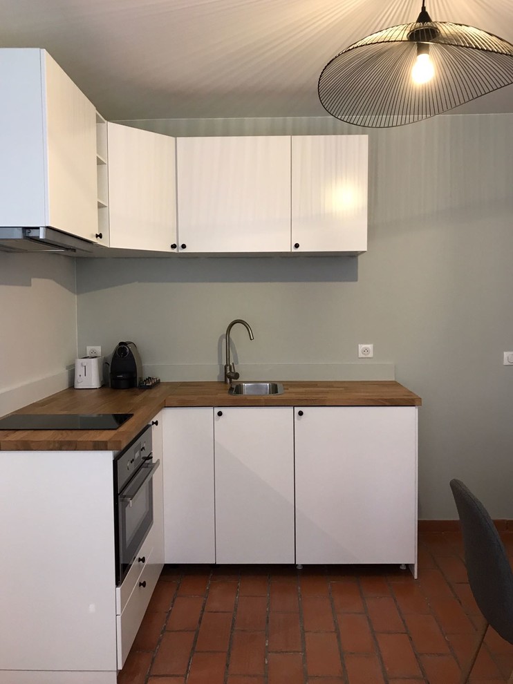 Photo of a small contemporary open plan kitchen in Lille with a submerged sink, beaded cabinets, white cabinets, wood worktops, integrated appliances, terracotta flooring, red floors and beige worktops.