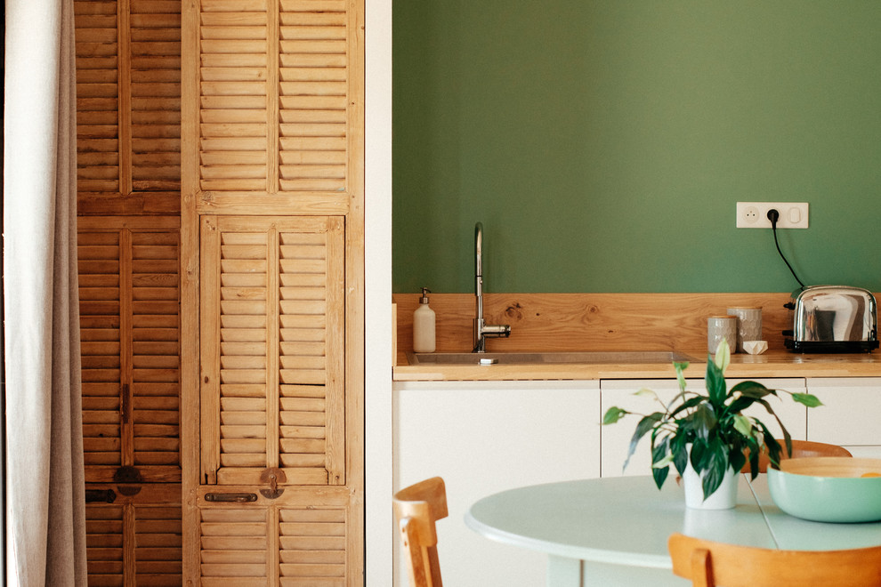 Aménagement d'une cuisine ouverte romantique en L et bois clair de taille moyenne avec un évier encastré, un placard à porte persienne, un plan de travail en bois, une crédence en bois, parquet clair et une crédence marron.