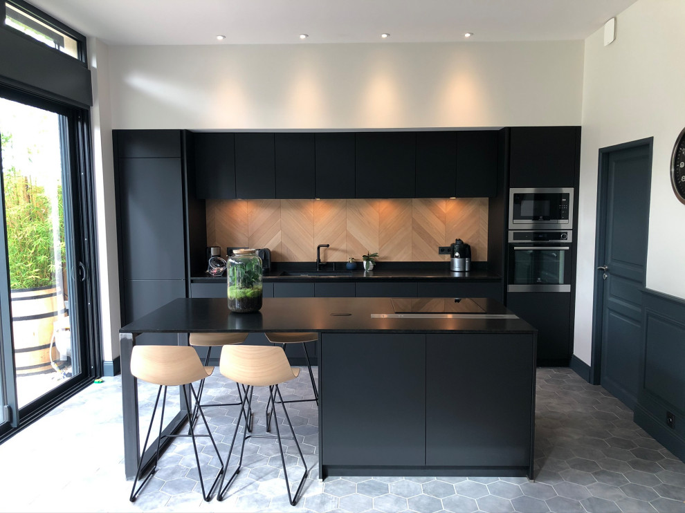 Photo of a large contemporary open plan kitchen in Lyon with a submerged sink, black cabinets, granite worktops, wood splashback, integrated appliances, cement flooring, an island, grey floors, black worktops and a drop ceiling.