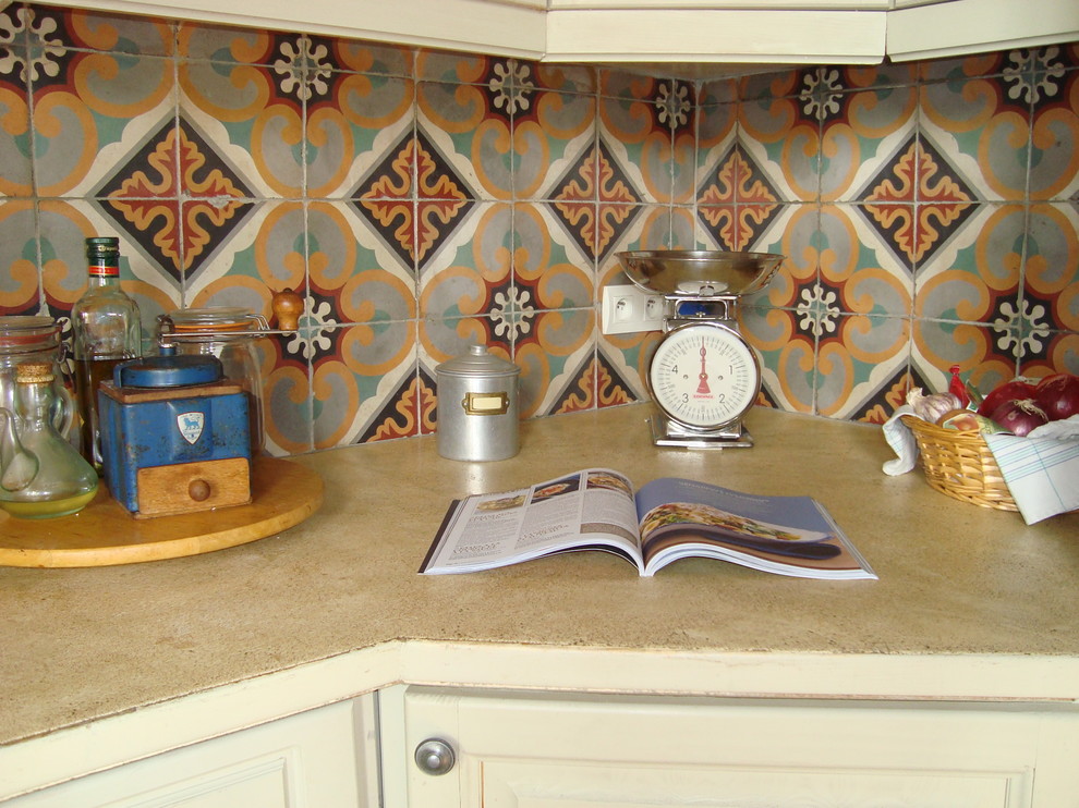 Cette image montre une grande cuisine ouverte rustique en L avec une crédence en céramique, tomettes au sol, un sol orange, un plan de travail beige, un placard à porte affleurante, des portes de placard beiges et une crédence multicolore.