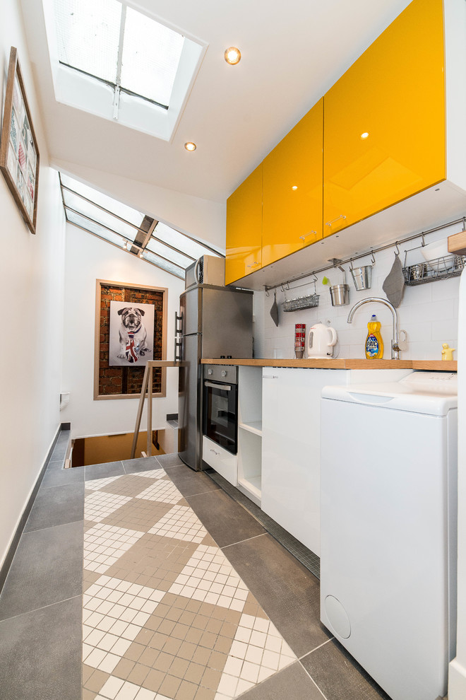 Foto på ett litet funkis linjärt kök med öppen planlösning, med släta luckor, gula skåp, träbänkskiva och vitt stänkskydd