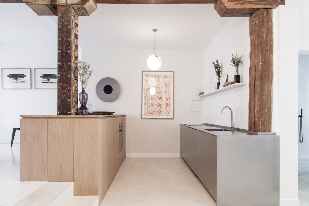 Immagine di una cucina minimal con ante lisce, ante in legno chiaro, pavimento in cemento, pavimento grigio e top grigio
