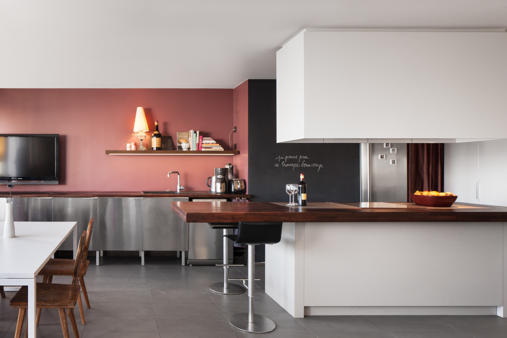 Foto på ett stort funkis kök, med skåp i rostfritt stål och en köksö