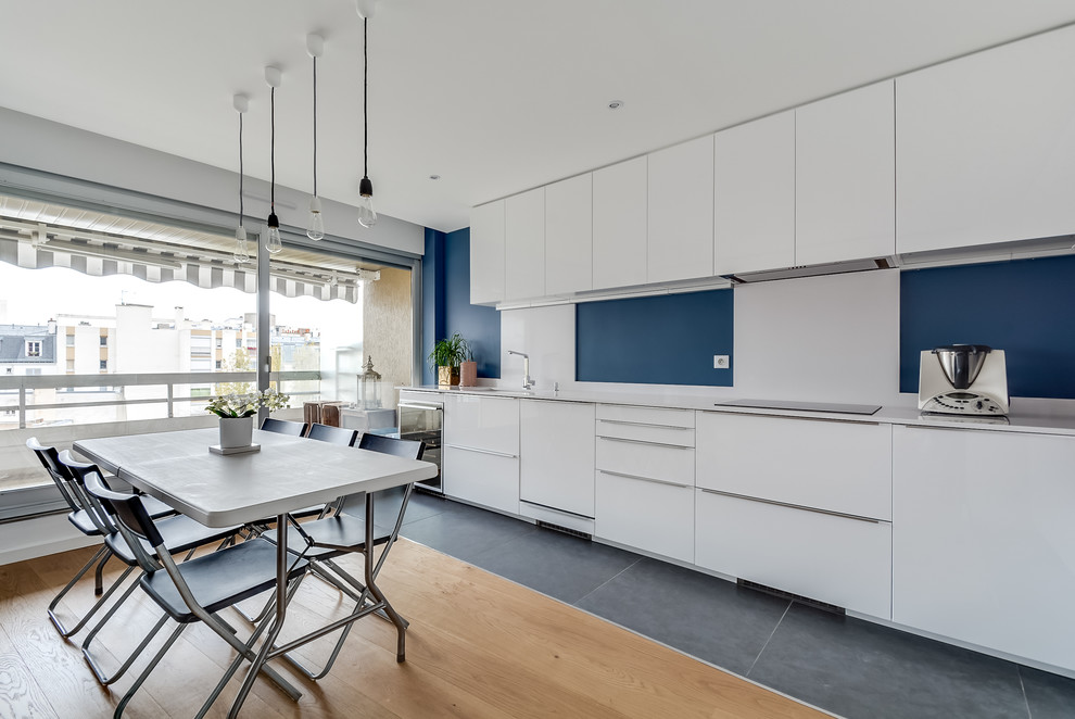 Inspiration for a large contemporary single-wall light wood floor eat-in kitchen remodel in Paris with flat-panel cabinets, white cabinets, blue backsplash and an undermount sink