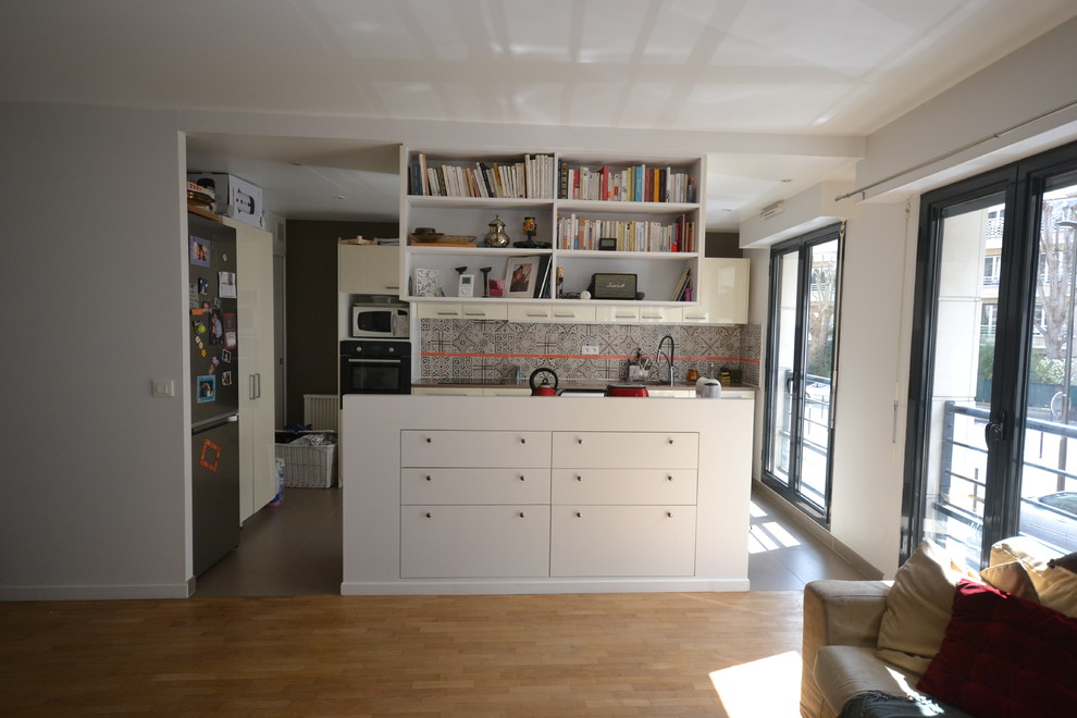 Bild på ett funkis kök med öppen planlösning, med en undermonterad diskho, släta luckor, beige skåp, bänkskiva i kvartsit, brunt stänkskydd, stänkskydd i cementkakel, svarta vitvaror, en köksö och grått golv