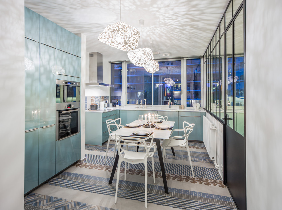 パリにあるコンテンポラリースタイルのおしゃれなキッチン (青いキャビネット、マルチカラーのキッチンパネル、シルバーの調理設備) の写真