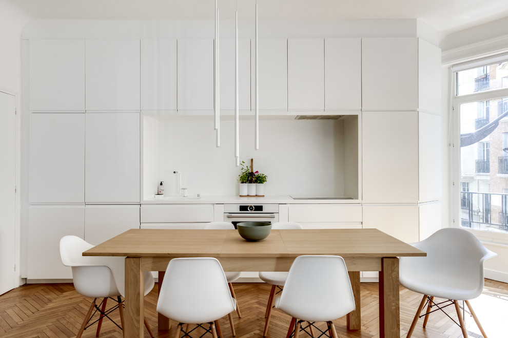 Immagine di una cucina design di medie dimensioni con ante bianche, paraspruzzi bianco, elettrodomestici bianchi, parquet chiaro, pavimento beige, top bianco e ante lisce