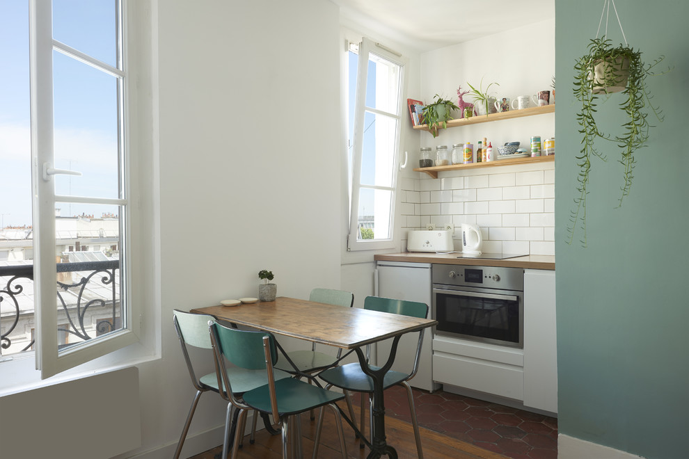 Exempel på ett skandinaviskt kök och matrum, med släta luckor, vita skåp, träbänkskiva, vitt stänkskydd, stänkskydd i tunnelbanekakel och rostfria vitvaror