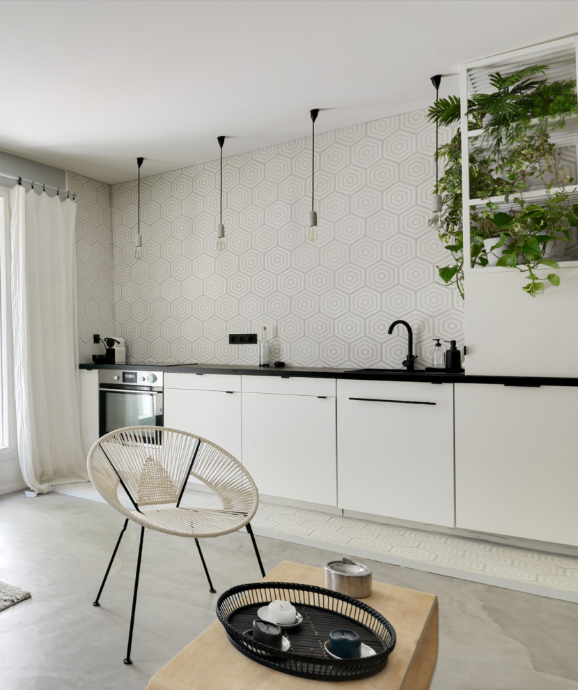 Small danish single-wall concrete floor and gray floor open concept kitchen photo in Paris with an undermount sink, beaded inset cabinets, white cabinets, granite countertops, gray backsplash, cement tile backsplash, paneled appliances, no island and black countertops