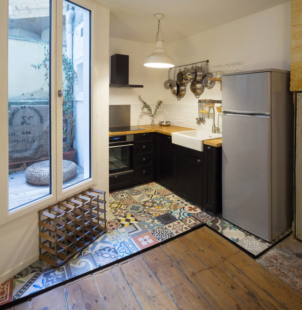 Immagine di una piccola cucina contemporanea con lavello sottopiano, ante nere, top in legno, paraspruzzi bianco, paraspruzzi con piastrelle diamantate, elettrodomestici in acciaio inossidabile e pavimento in cementine