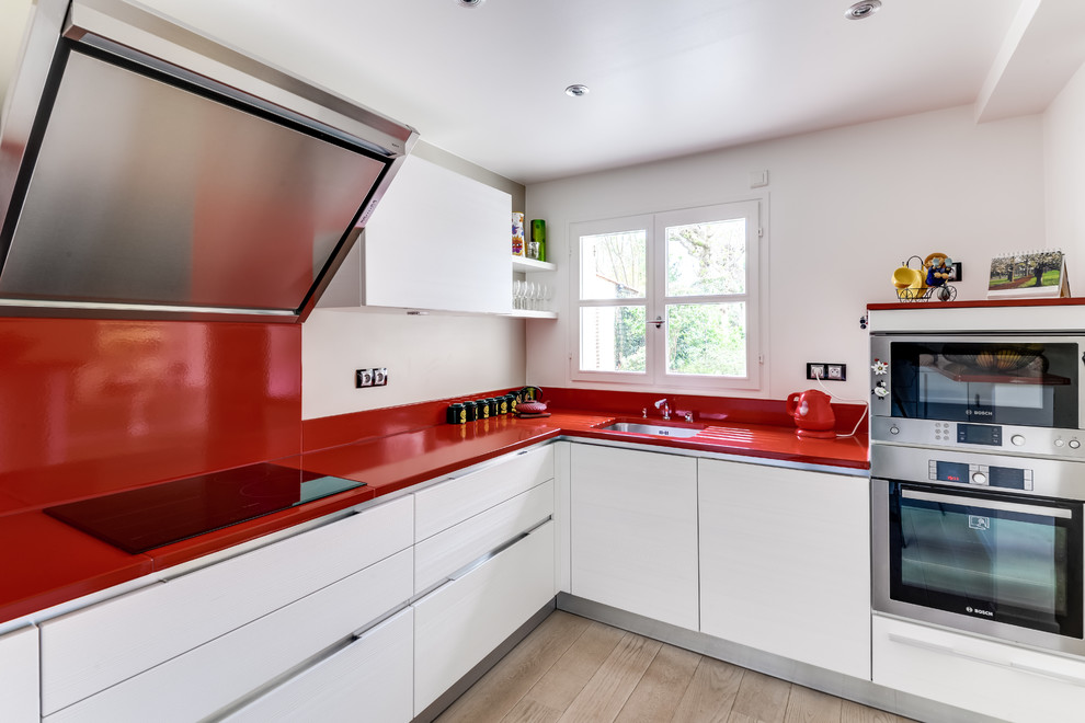 Enclosed kitchen - mid-sized contemporary l-shaped light wood floor and brown floor enclosed kitchen idea in Paris with a single-bowl sink, flat-panel cabinets, white cabinets, red backsplash, stainless steel appliances, no island, red countertops, quartzite countertops and subway tile backsplash