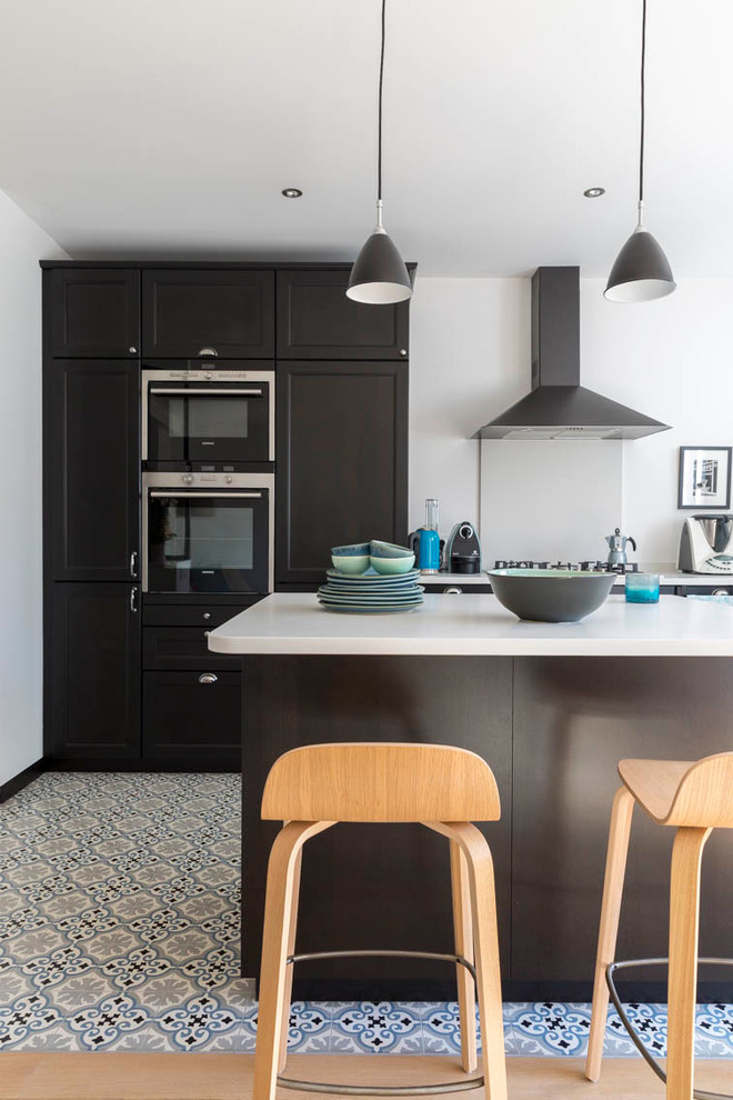 Immagine di una cucina minimal di medie dimensioni con top in superficie solida, pavimento con piastrelle in ceramica, paraspruzzi bianco, lavello sottopiano, elettrodomestici da incasso e pavimento multicolore