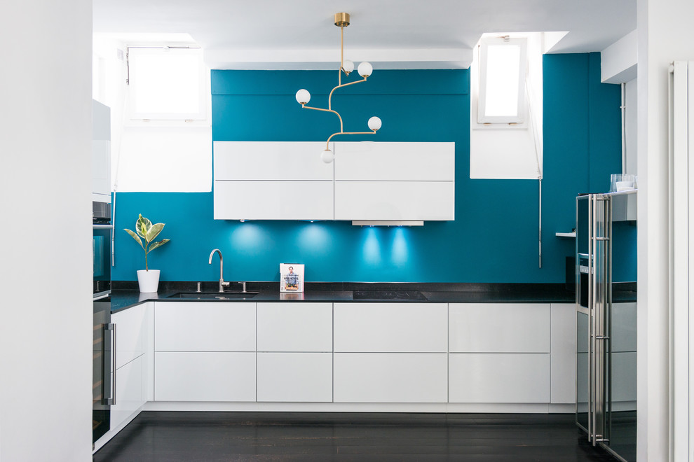 Inspiration för ett mellanstort funkis kök, med en integrerad diskho, vita skåp, granitbänkskiva, blått stänkskydd, svarta vitvaror, målat trägolv och svart golv