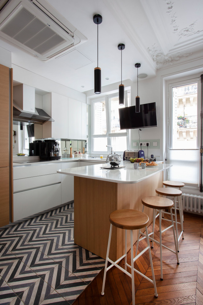 Modern inredning av ett stort vit vitt kök, med släta luckor, skåp i ljust trä, bänkskiva i kvartsit, stänkskydd med metallisk yta, spegel som stänkskydd, mellanmörkt trägolv, en köksö och blått golv
