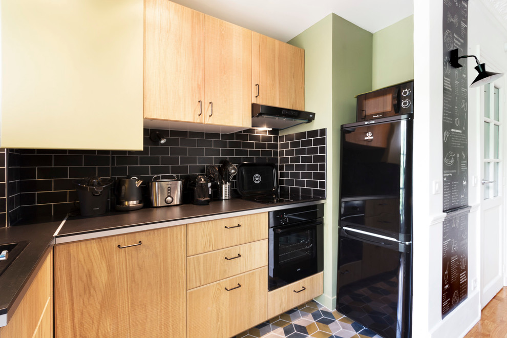 Exempel på ett litet modernt kök, med en enkel diskho, luckor med profilerade fronter, skåp i ljust trä, laminatbänkskiva, svart stänkskydd, stänkskydd i tunnelbanekakel, svarta vitvaror och klinkergolv i terrakotta