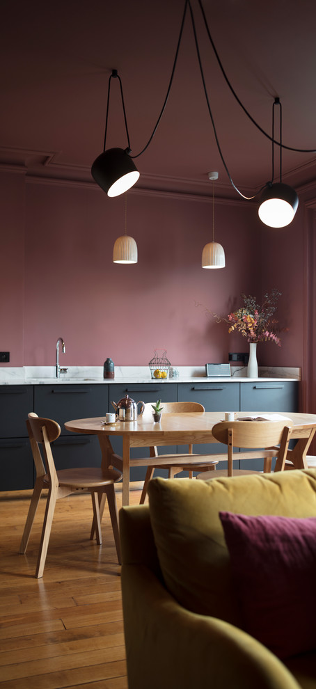 Expansive contemporary single-wall kitchen/diner in Paris with black cabinets, marble worktops and marble splashback.