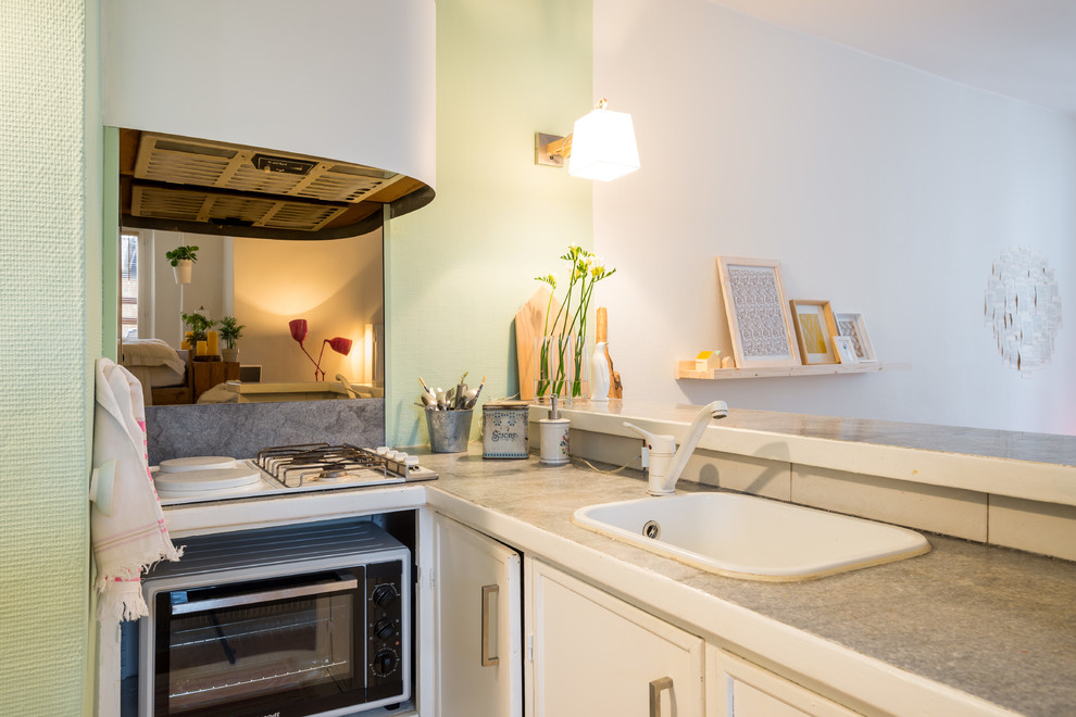 Aménagement d'une petite cuisine ouverte encastrable scandinave en L avec un évier posé, des portes de placard blanches et une crédence miroir.