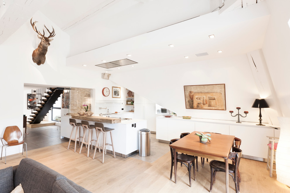 Example of a mid-sized danish l-shaped light wood floor open concept kitchen design in Lyon with flat-panel cabinets, white cabinets, white backsplash and a peninsula