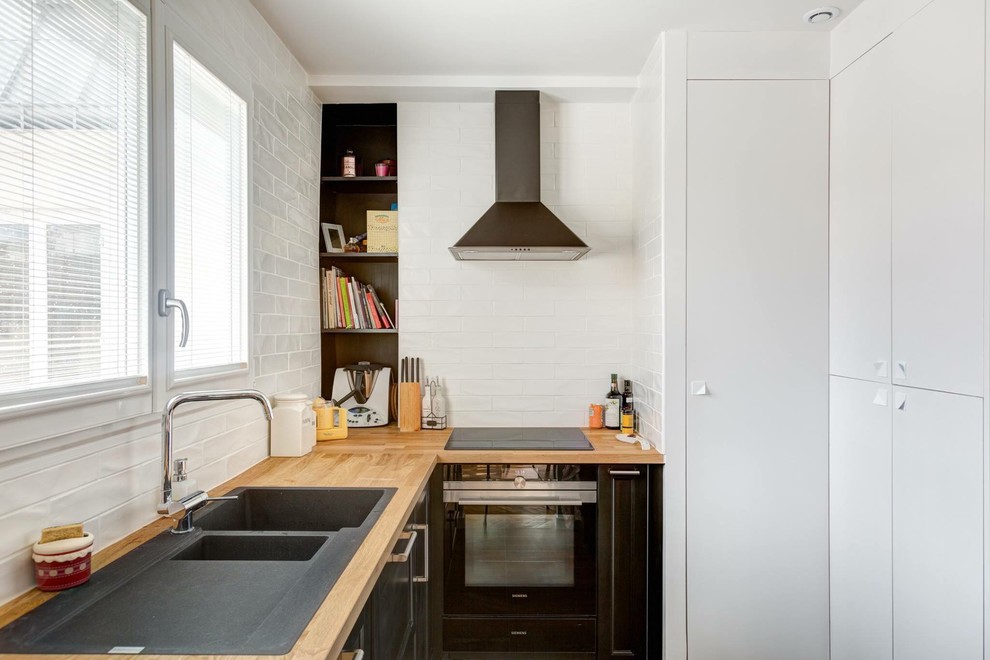 Idéer för att renovera ett litet funkis l-kök, med en dubbel diskho, träbänkskiva, vitt stänkskydd, stänkskydd i tunnelbanekakel, släta luckor, vita skåp och svarta vitvaror