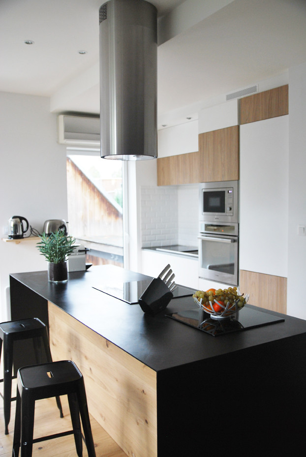 Zweizeilige, Mittelgroße Moderne Küche mit Vorratsschrank, Küchenrückwand in Weiß, Rückwand aus Keramikfliesen, Küchengeräten aus Edelstahl, braunem Holzboden und Kücheninsel in Nantes