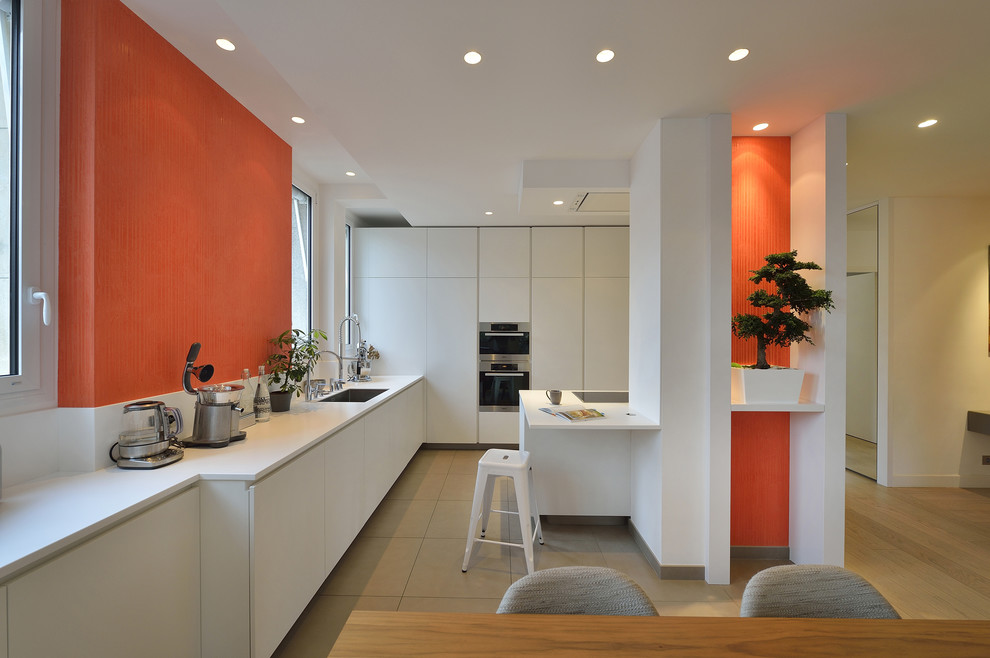Einzeilige, Große Moderne Wohnküche mit weißen Schränken, Küchenrückwand in Weiß und Kücheninsel in Paris