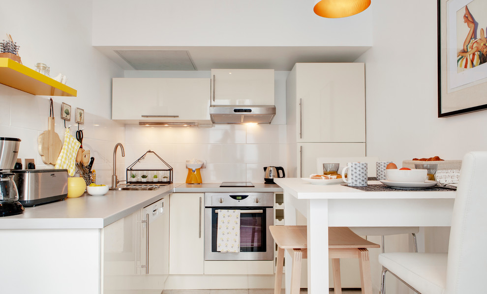 Kleine Moderne Wohnküche in L-Form mit flächenbündigen Schrankfronten, weißen Schränken, Küchenrückwand in Weiß, Rückwand aus Keramikfliesen und Elektrogeräten mit Frontblende in Paris